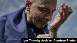 Ihor Titovski își leagă la mână o brățară în culorile Ucrainei, imediat după eliberarea sa din captivitate și întoarcerea în țară, în septembrie 2024. A fost capturat la Mariupol în mai 2022. 