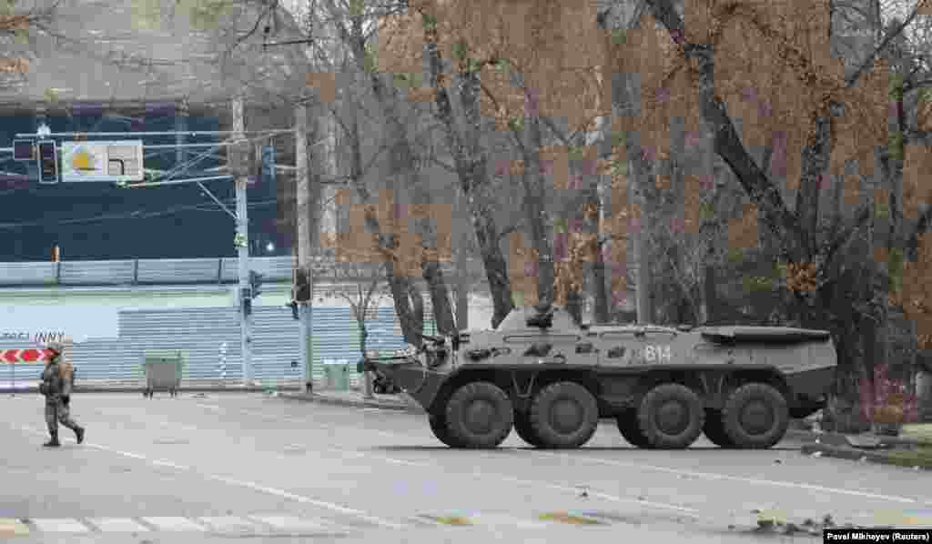 Një pjesëtar i shërbimit kazak duke ecur afër një transportuesi të blinduar pas protestave të shkaktuara nga rritja e çmimit të karburantit, qyteti Almati, Kazakistan, 7 janar 2022. 