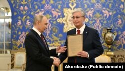 Ресей президенті Владимир Путин (сол жақта) Қазақстан президенті Қасым-Жомарт Тоқаевқа әкесі Кемел Тоқаевтың марапат құжатын табыс етіп тұр. Мәскеу, 9 мамыр, 2025 жыл