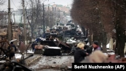 Украина, луѓе гледаат кон остатоци од руските воени возила на патот кон Буча, град во близина на Киев 