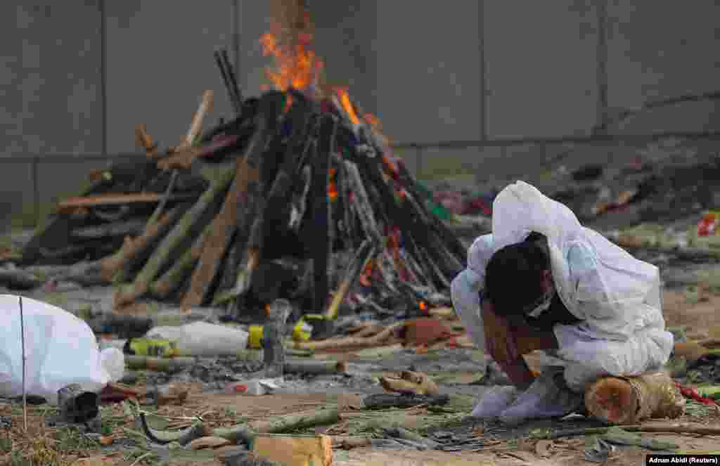 Un bărbat plânge în timp ce stă lângă rugul aprins al unei rude, care a murit din cauza COVID-19, în timpul incinerării sale, la un crematoriu din New Delhi, India, 5 mai 2021. REUTERS / Adnan Abidi