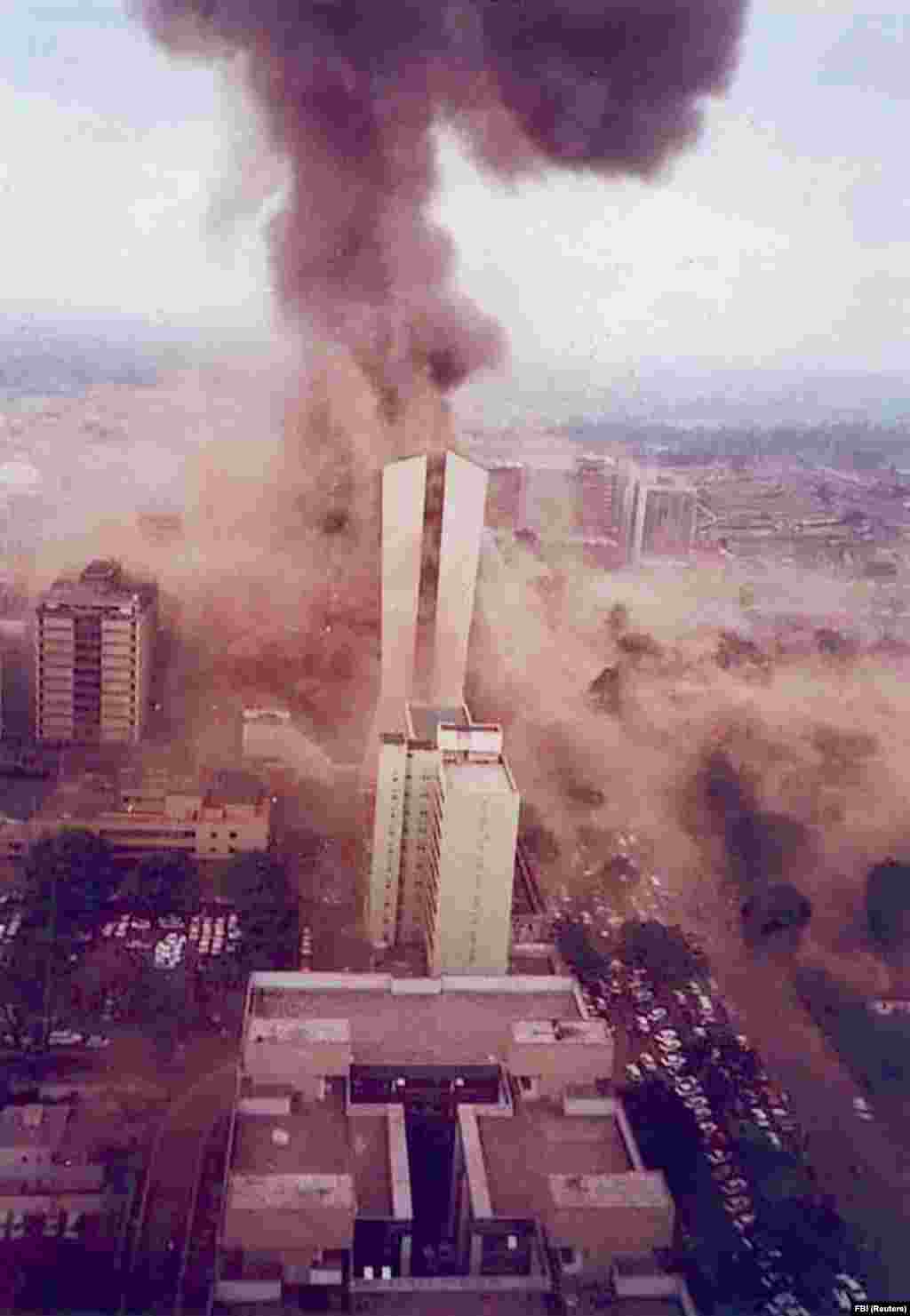 Найроби, Кения, 1998 жыл. АҚШ елшілігіндегі жарылыстың түтіні. Елшілік ғимаратында террористер бомбамен жабдықтаған жүк көлігі жарылған. 1990-жылдары Бен Ладен бірнеше террор шабуылдарын өзі ұйымдастырғанын айтқан. Олардың арасында АҚШ елшілігіндегі осы жарылыс та бар. Жарылыс кезінде қаза тапқандардың 224-і жергілікті африкалық болған.