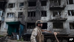 Un soldat ucrainean trecând pe lângă un bloc de locuințe grav avariat la Ceasiv Iar, în mai 2023.