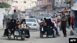 În imagine, palestinieni din orașul Khan Yunis părăsesc, luni 22 iulie, zona orașului unde armata israeliană a ordonat evacuarea.