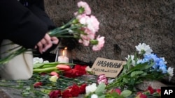 O femeie aduce un omagiu lui Alexei Navalnîi la monumentul în memoria victimelor represiunilor politice din URSS, Sankt Petersburg, Rusia, 21 februarie 2024.
