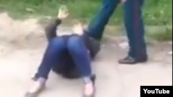 Узбекский милиционер пинает в лицо и голову лежащей на земле женщины. 