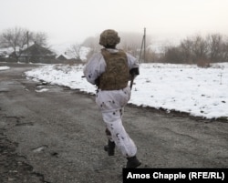 Un soldat ucrainean fuge în timp ce privește spre pozițiile separatiștilor din apropiere, susținuți de Rusia, în regiunea Lugansk - 7 decembrie.
