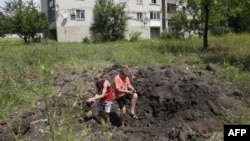 Ուկրաինա - Լուգանսկի շրջանի Պոպասնա քաղաքում երեխաները խաղում են արկակոծման հետևանքով առաջացած փոսում, արխիվ