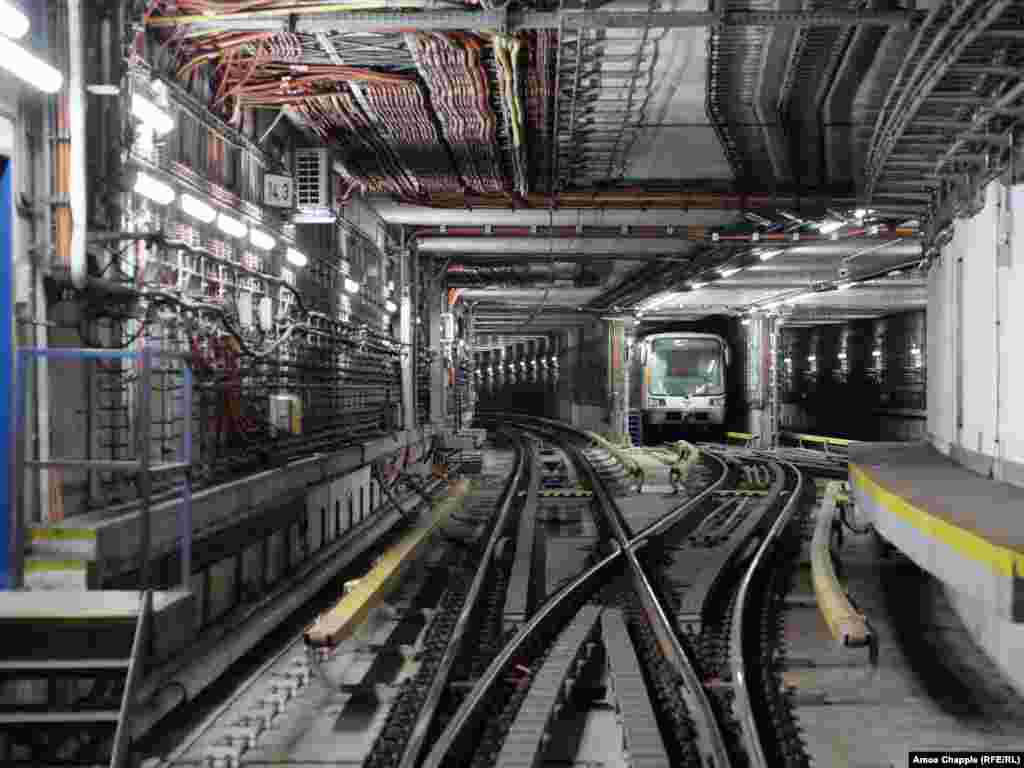 Un tren de metrou își începe prima călătorie a zilei în timp ce o ușă antiexplozie este testată în apropiere. Astăzi, autoritățile din Praga descriu scopul OSM ca fiind atât &bdquo;protejarea populației împotriva efectelor armelor de distrugere în masă pentru o perioadă de 72 de ore&rdquo;, cât și &bdquo;izolarea secțiunilor metroului în cazul unei inundații majore&rdquo;.