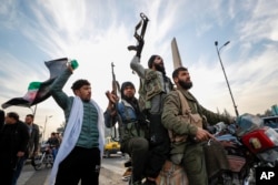 Luptători ai opoziției siriene salutând căderea regimului Assad în Damasc, pe 8 decembrie.