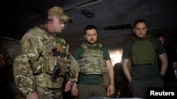 Președintele ucrainean Volodimir Zelenski (centru) vizitează trupele de operațiuni speciale de lângă Bahmut pe 29 iulie.
